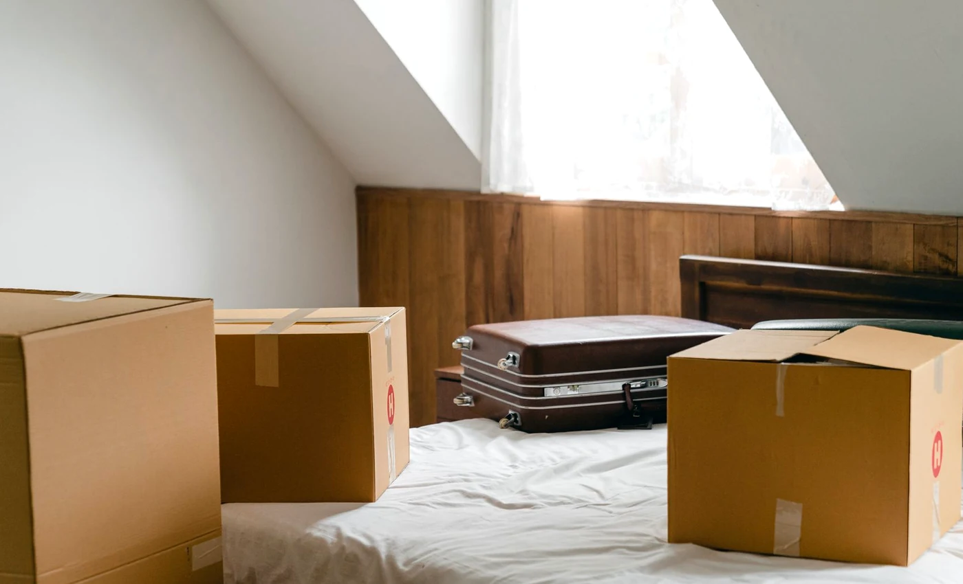 Kartons und Koffer in einem hellen Zimmer als Symbolbild für Teilräumung einzelner Räume.